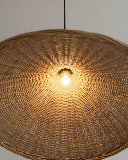 Close-up of a handwoven rattan pendant light with a sculptural wave shade; warm 2700K glow and visible E27 bulb show the radial weave detail—ideal above a kitchen island or dining table.