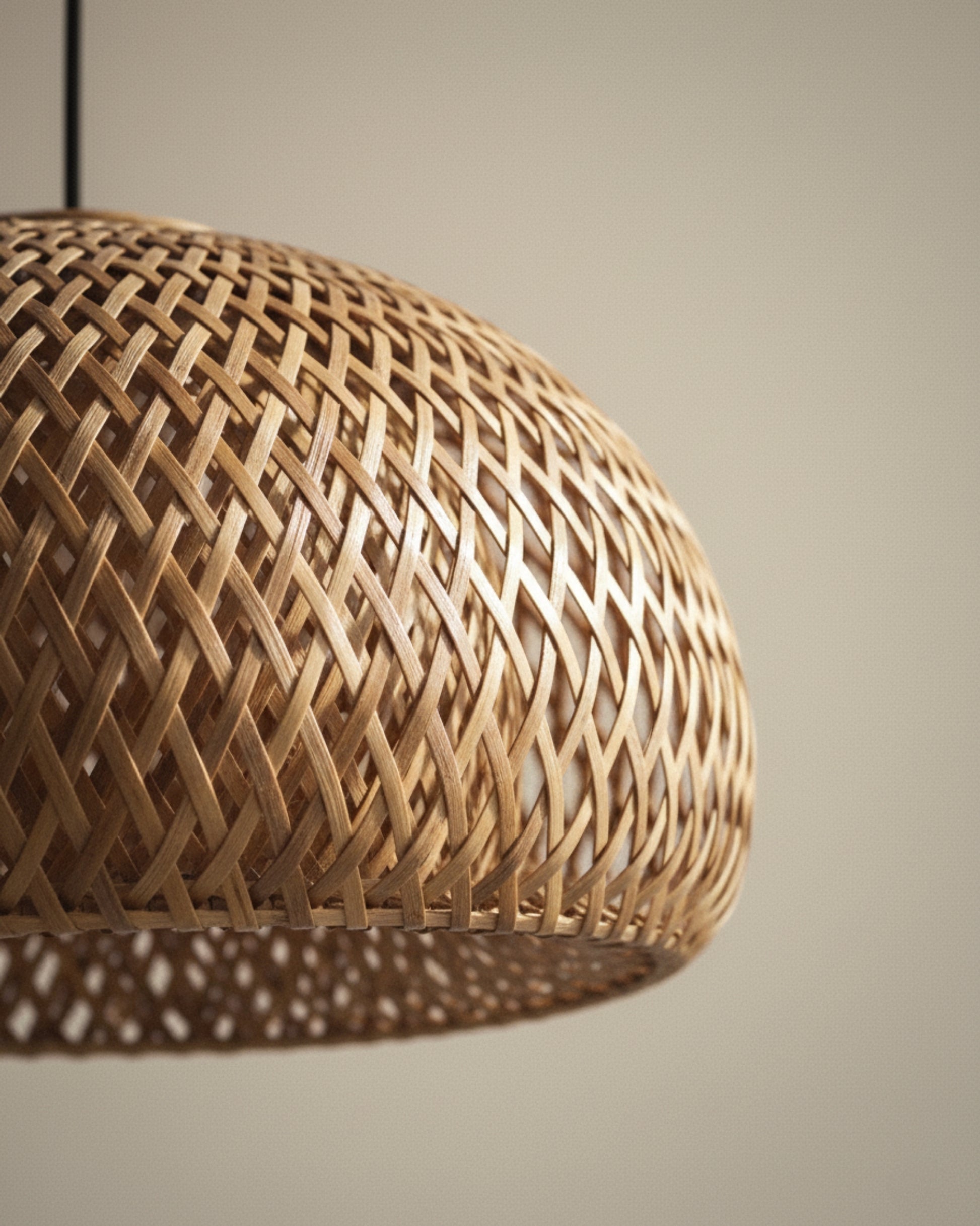 Close-up of a handwoven bamboo dome pendant lampshade, showing tight diamond lattice and rim detail; warm honey finish under soft studio lighting, subtle shadows, black suspension cord at the edge, neutral beige background.