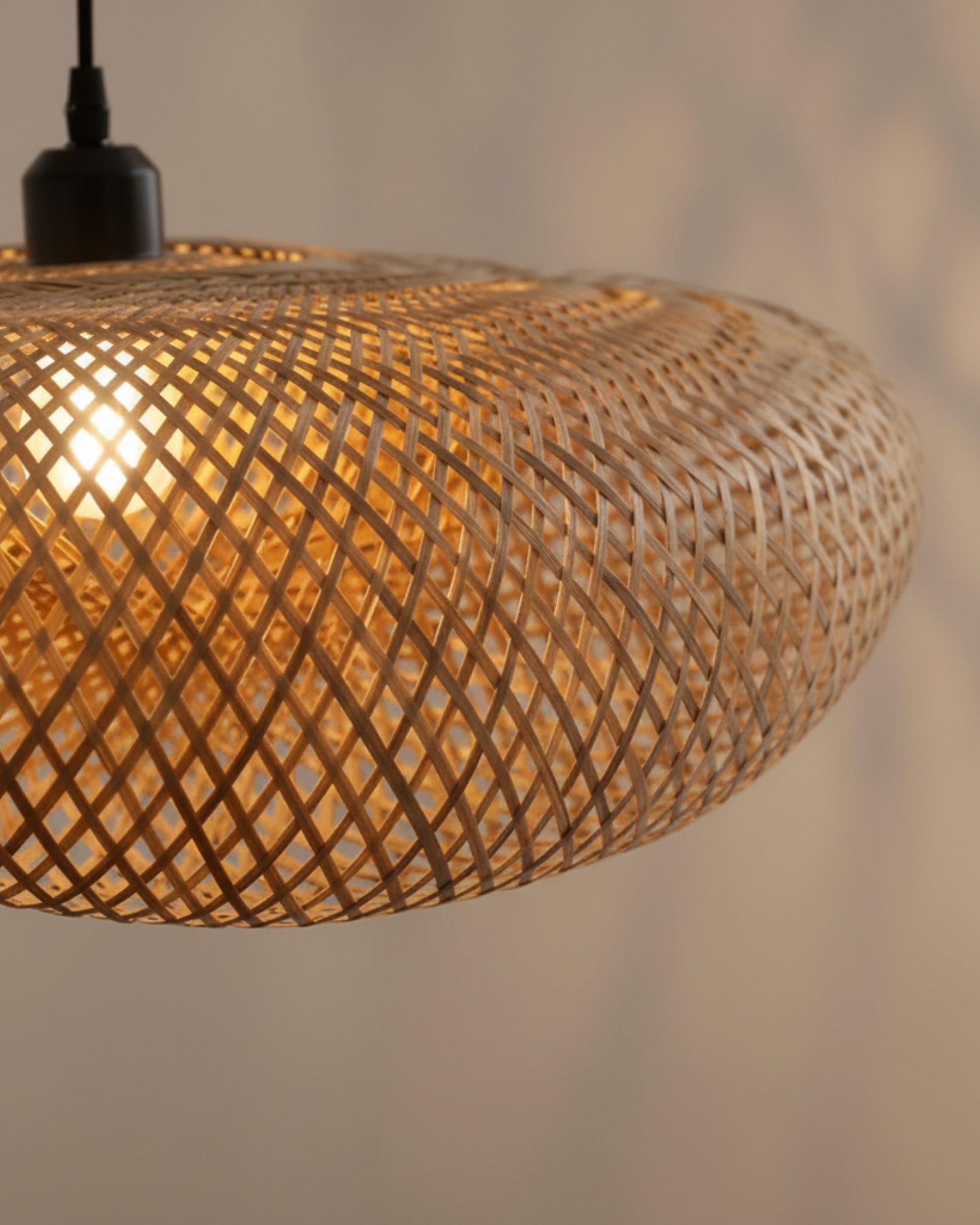 Close-up of a handwoven bamboo twisted-disc pendant with black E27 socket and slim cord; warm 2700K bulb ON glowing through the lattice and casting soft shadows; approx. 31.5 in (80 cm) diameter; ideal over a kitchen island or dining table.