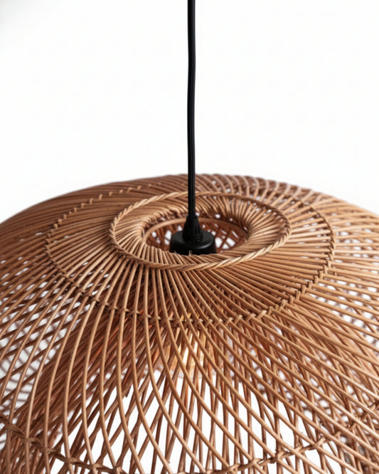 Close-up of a handwoven rattan pendant shade showing the spiral lattice and central ring with black cord; natural honey-brown finish and airy weave that casts patterned light—ideal for Japandi/Scandi interiors.