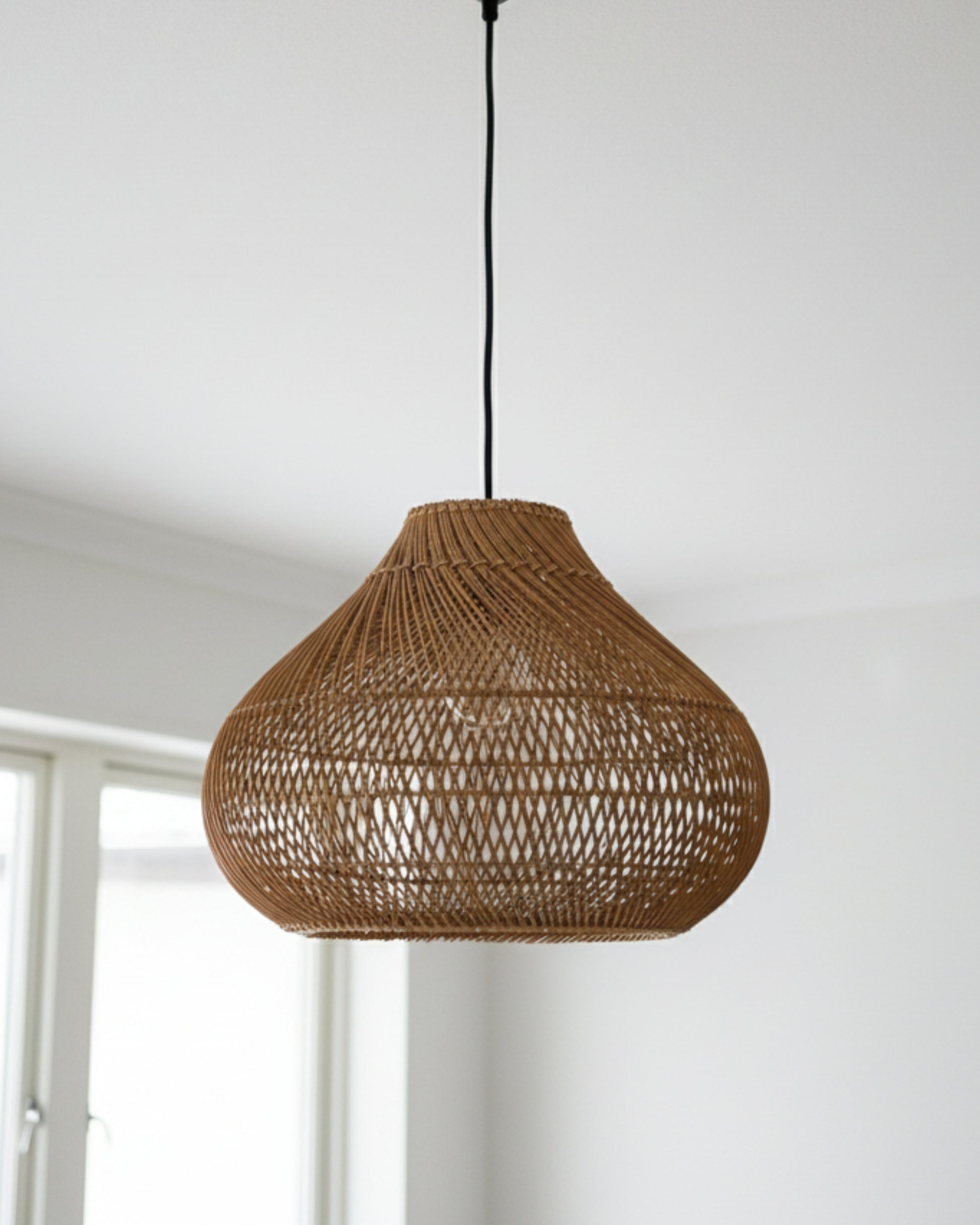Close-up of a gourd-shaped handwoven rattan pendant with black cord,D40 cm (15.75”) × H33 cm (12.99”); airy lattice weave, E27 compatible. Shown unlit by a window in a bright neutral room—ideal for living rooms or bedrooms.