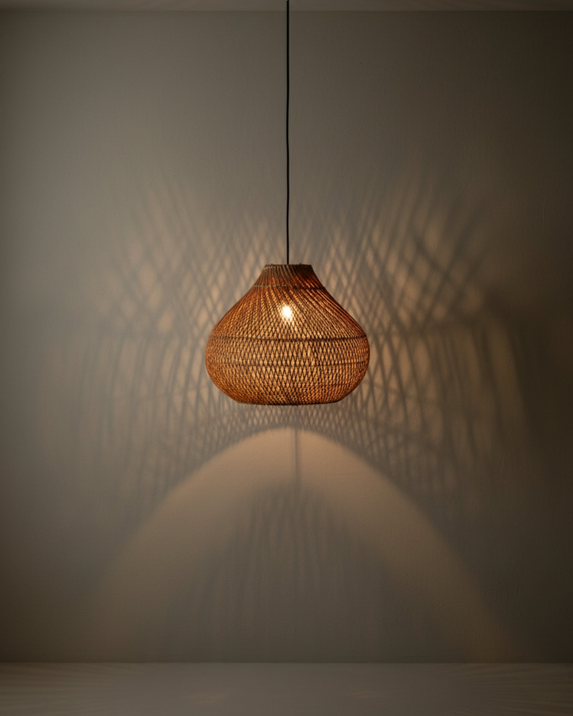 Gourd-shaped handwoven rattan pendant with black cord, D40 cm (15.75”) × H33 cm (12.99”), E27 LED. Warm lattice pattern projects onto the wall and table below, creating a soft ambient pool—ideal for cozy dining nooks or bedside corners.