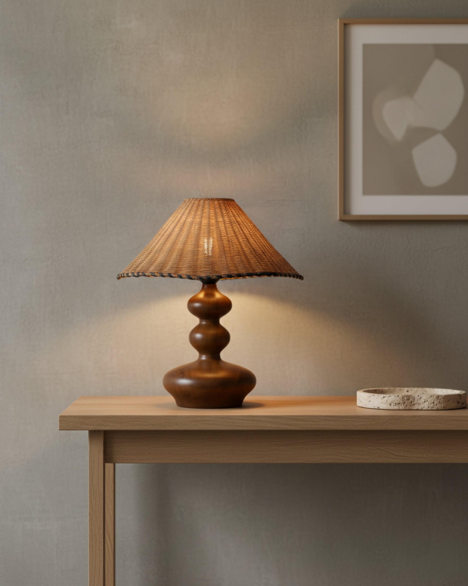 Handwoven rattan table lamp with conical 40 cm (15.75") shade and sculpted ash-wood base in walnut tone, lit on a light-oak console against a plaster wall; warm 2700K glow for a minimalist Japandi living room.